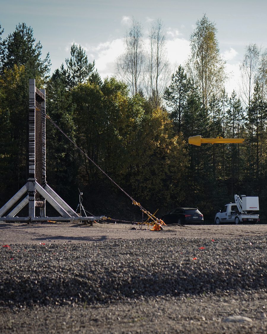 Keltainen droonimalli lennossa kohti testikehikon verkkoa
